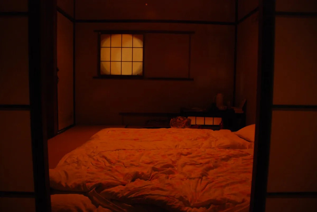 A traditional ryokan hallway with paper lanterns and wooden screens glowing softly in Nara Japan