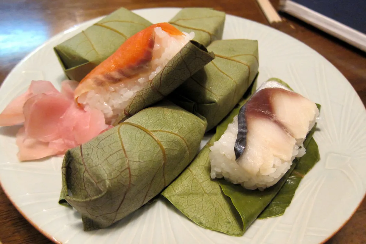 Kakinohazushi persimmon leaf sushi displayed at a traditional Nara shop, wrapped in green leaves with mackerel filling