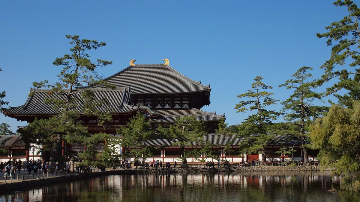Todaiji temple’s great wooden Daibutsuden hall rising above the forested hills of Nara with a clear blue sky