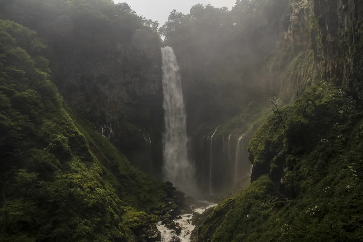 Kegon waterfall cascading 97 meters into the rocky basin below with lush green forest surrounding the dramatic drop in Nikko, Japan