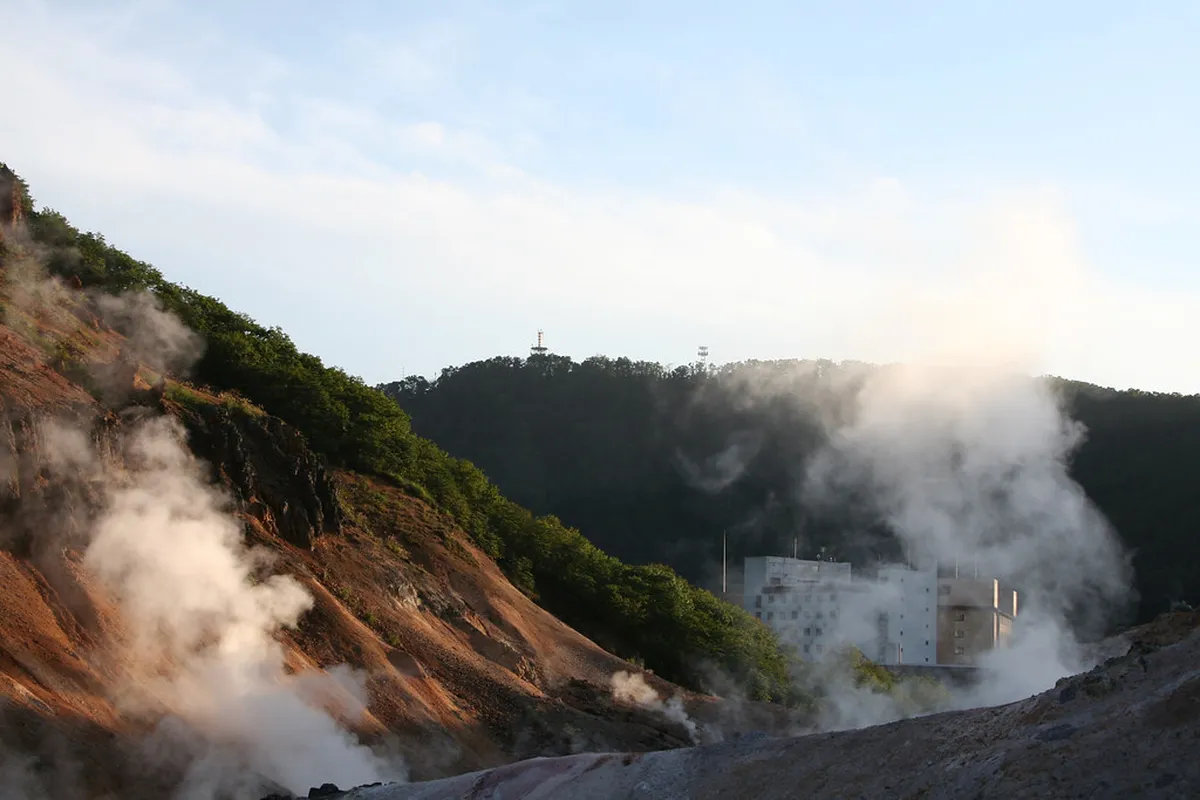 Bathers relaxing in a traditional Japanese onsen hot spring pool with steam rising in the air, Japan