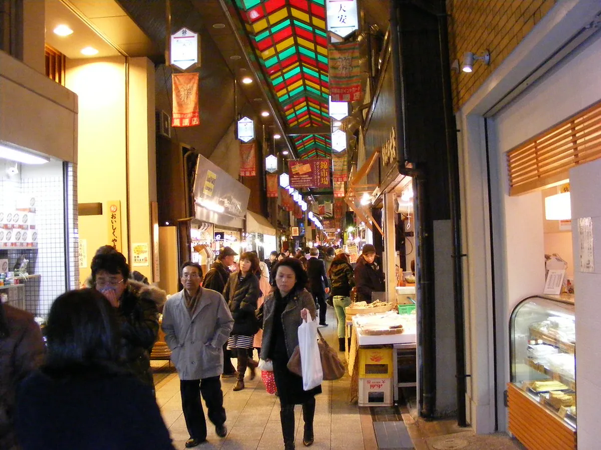 Nishiki Market covered arcade in central Kyoto with colorful stall fronts and shoppers along the narrow lane