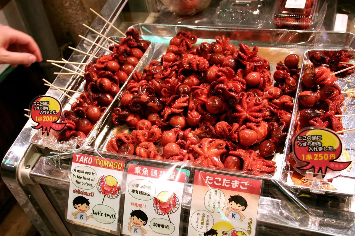Street food stalls at Nishiki Market Kyoto serving fresh snacks including skewered octopus and seasonal sweets