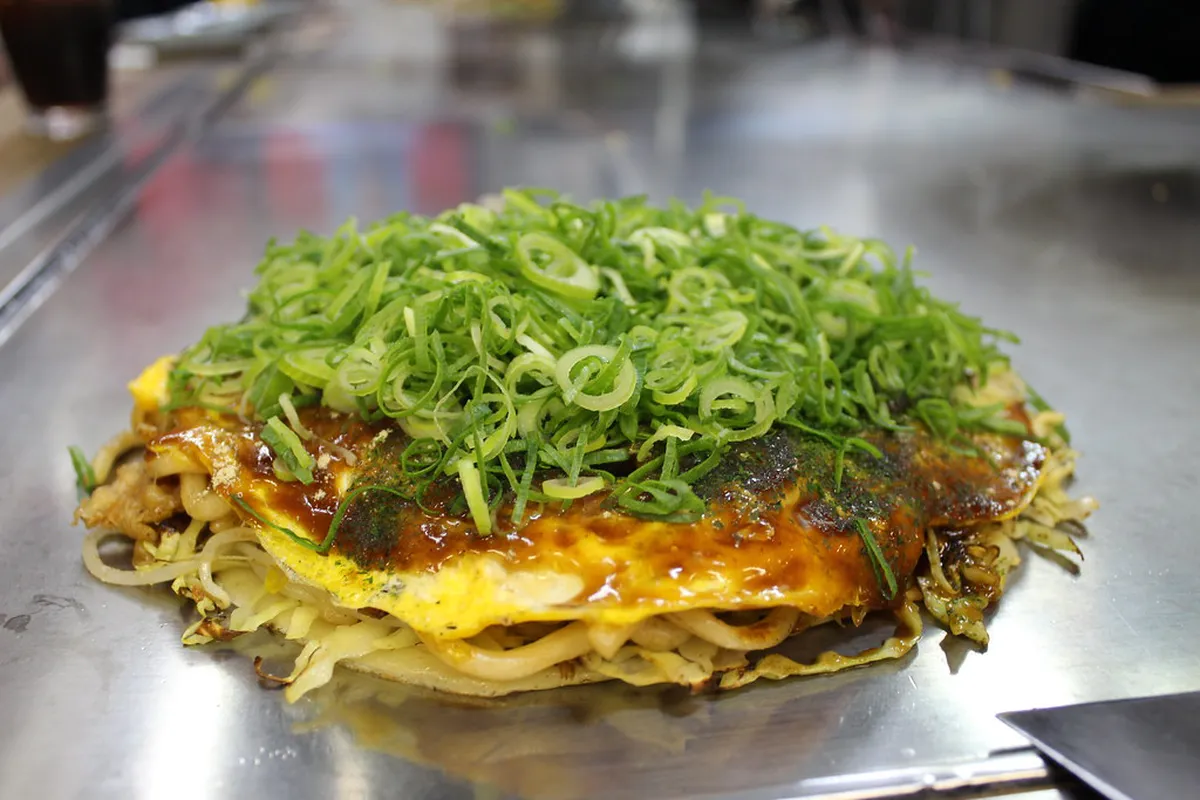 Busy Okonomimura food stalls with chefs cooking on iron griddles in the multi-storey building in Hiroshima