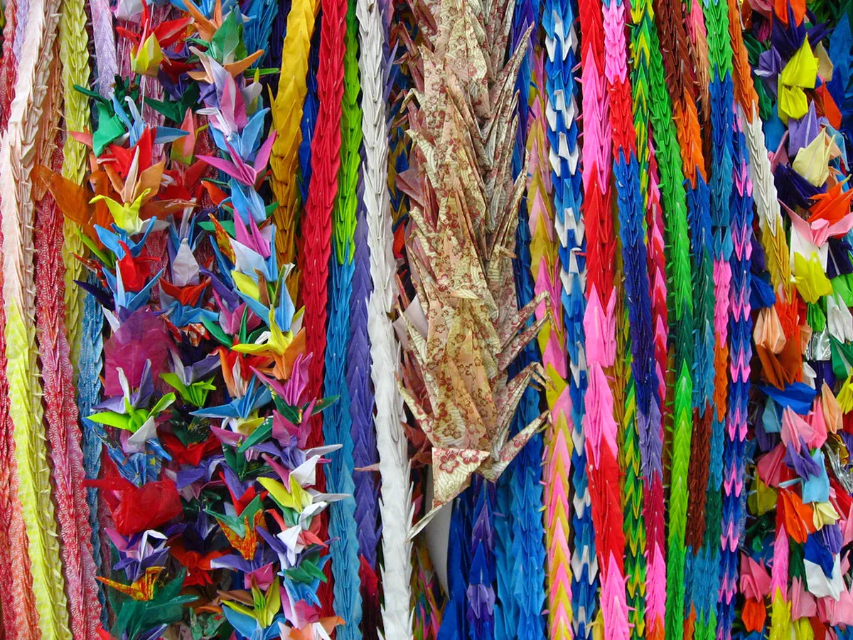 Colorful folded paper cranes collected inside the glass Orizuru Wall installation at Orizuru Tower in Hiroshima
