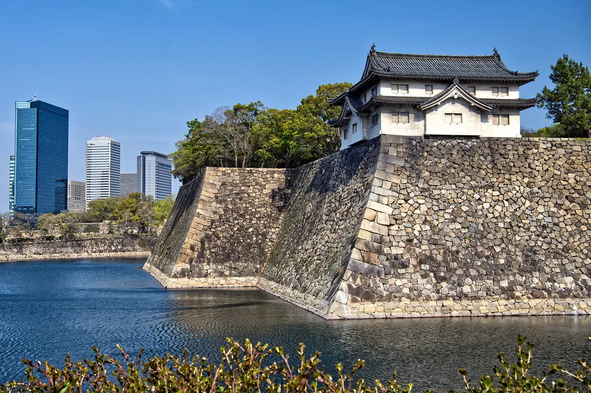 Osaka Castle towering above the park grounds with cherry blossom trees in bloom in Japan