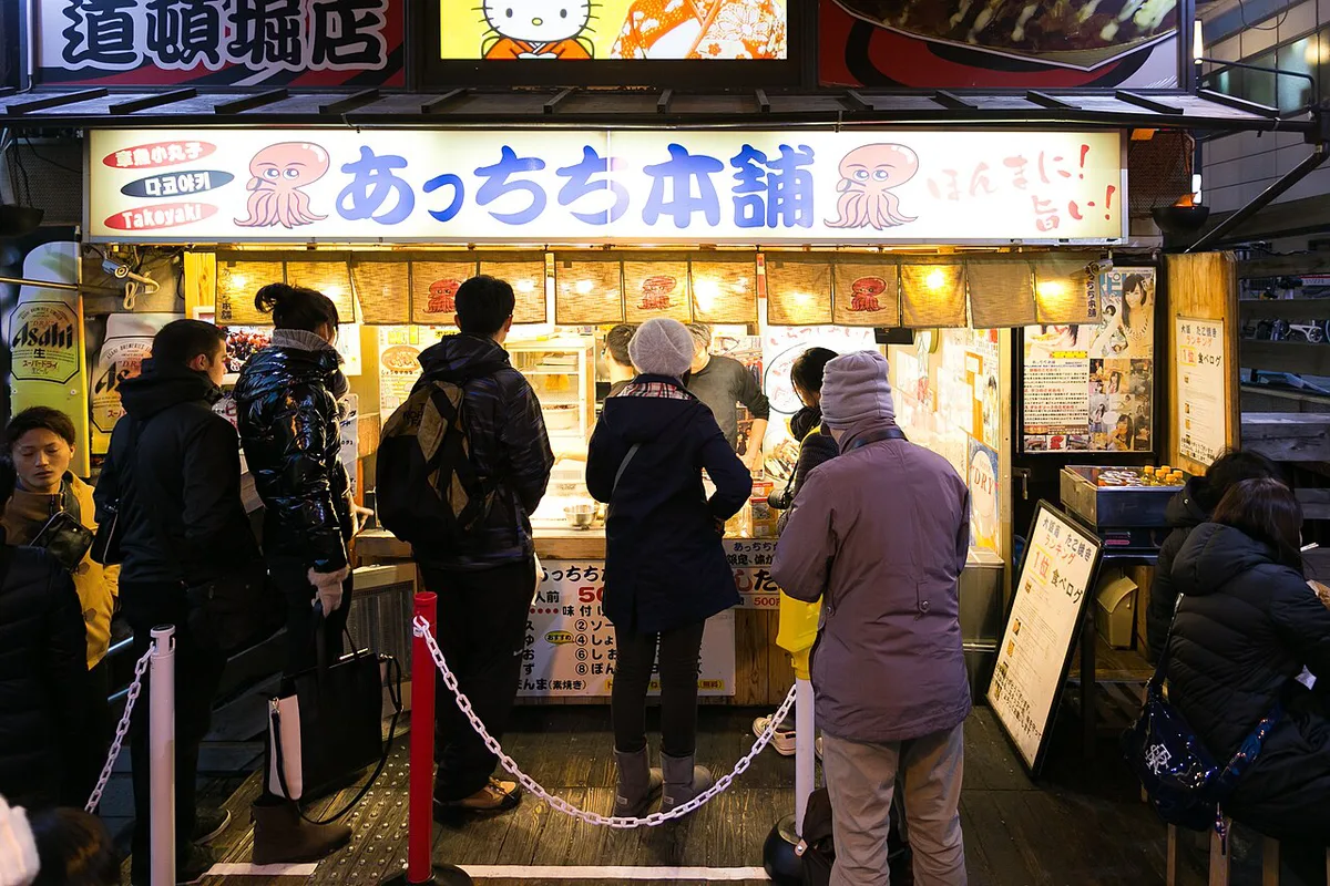 Takoyaki and okonomiyaki spread with Dotonbori canal in the background, Japan — 1