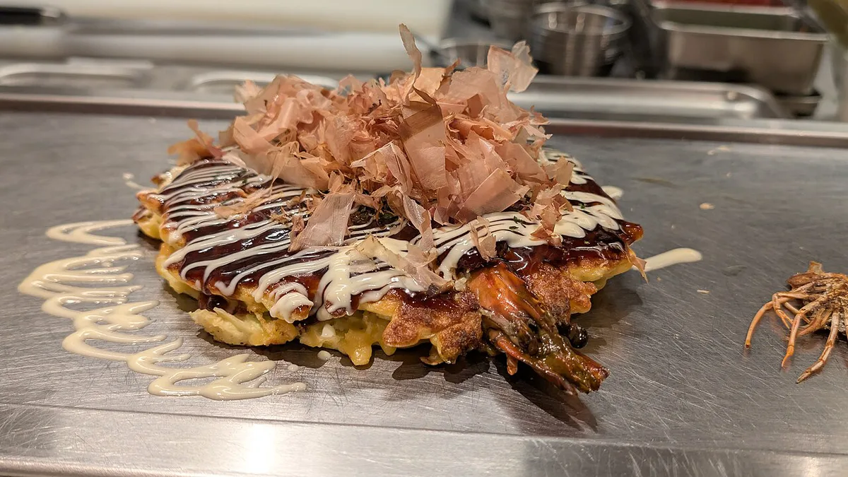 Takoyaki and okonomiyaki spread with Dotonbori canal in the background, Japan — 2