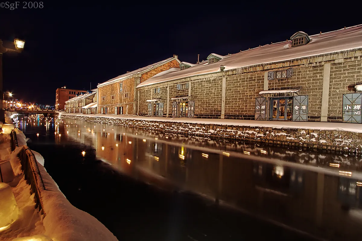 Otaru canal in Hokkaido Japan lined with historic stone warehouses dusted in snow on a crisp winter afternoon