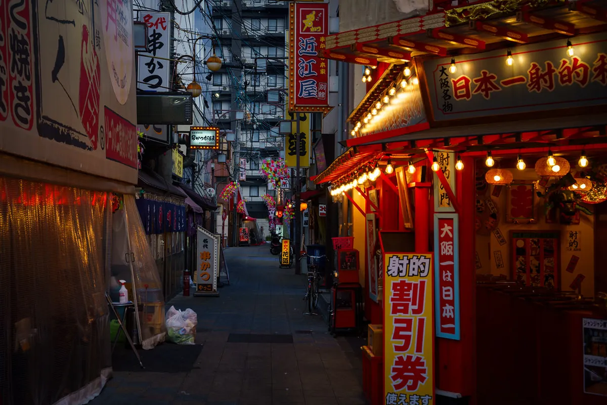 Shinsekai retro district streets with colorful shop signs and the Tsutenkaku Tower visible in Osaka, Japan