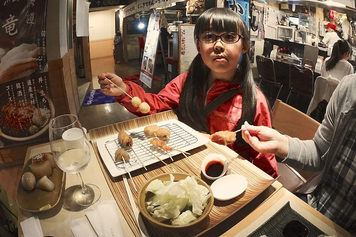 SAKURAKO eats the Kushi-Katsu (Japanese dish of deep-fried skewered meat and vegetables). (27636623640) — 2