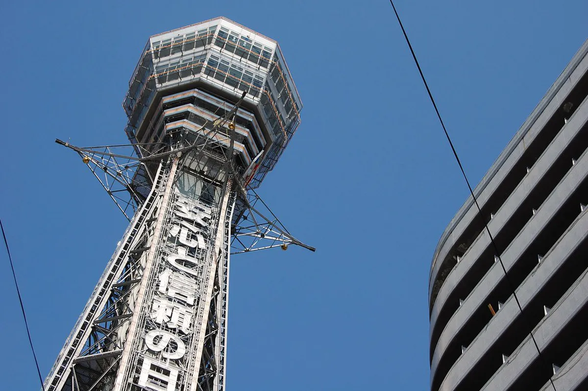 Tsutenkaku Tower rising above the Shinsekai district streets lit up with neon signs in Osaka, Japan