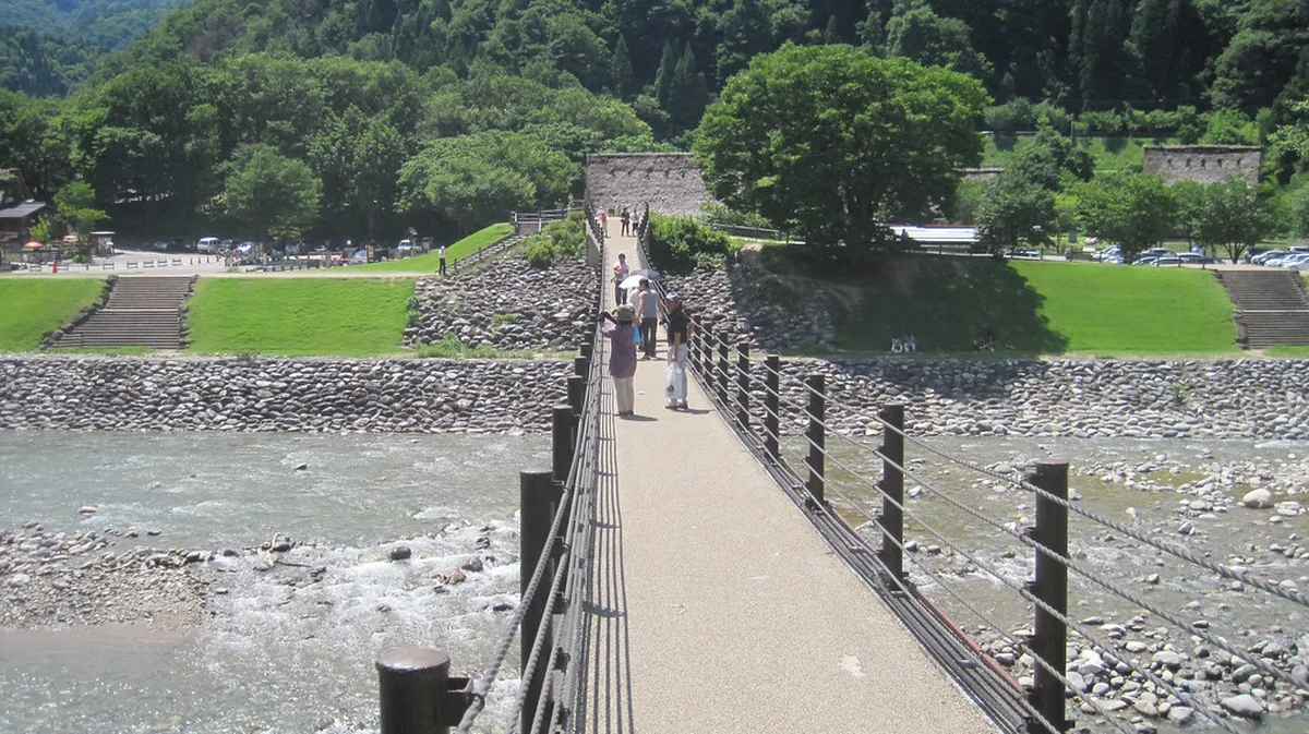 Deai suspension bridge crossing the Shogawa River with Shirakawa-go village farmhouses in background