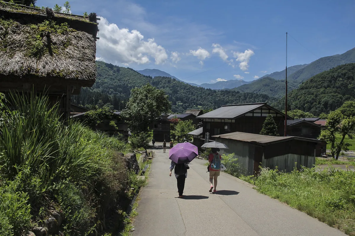 Visitors walking through the historic Ogimachi village of Shirakawa-go past traditional thatched gassho-zukuri homes in Japan