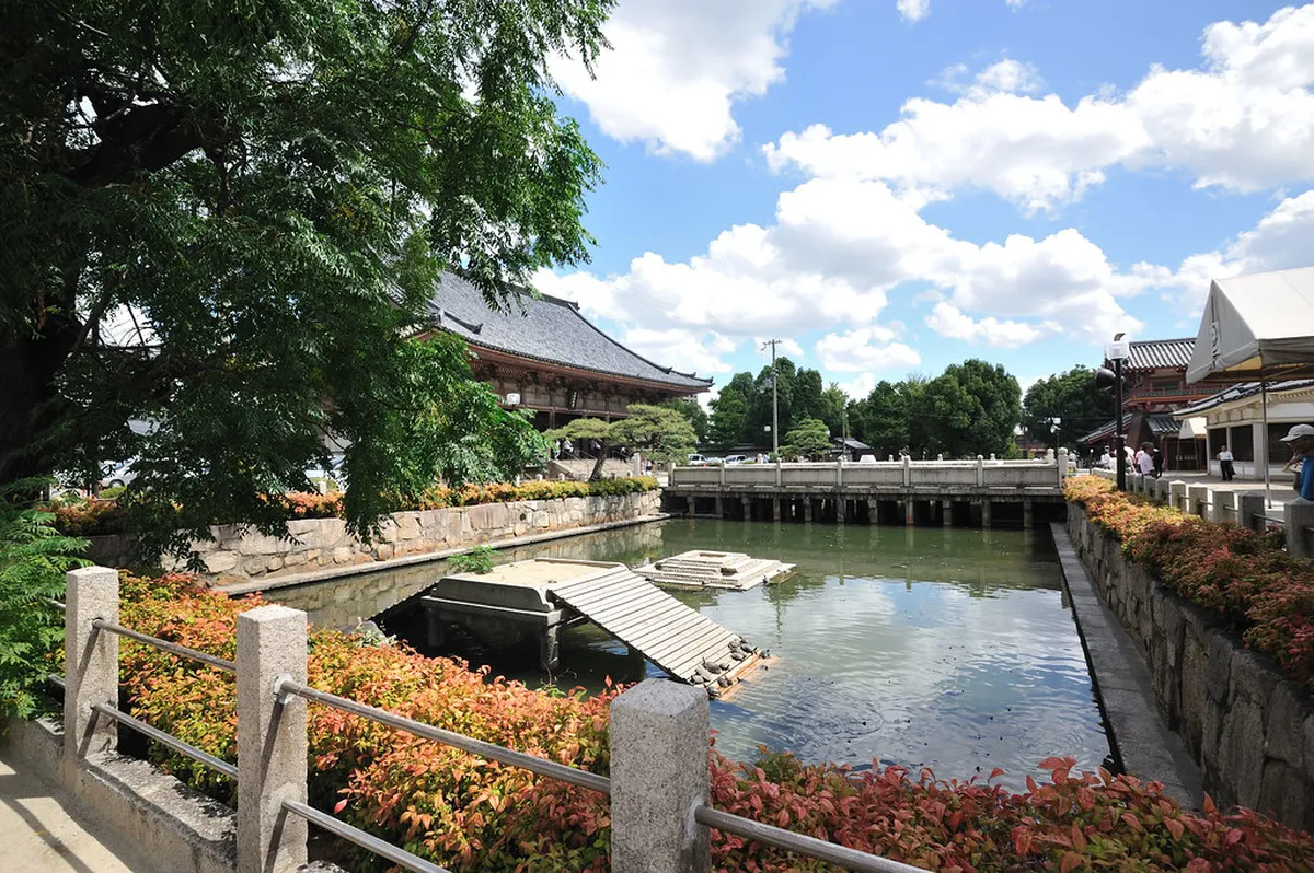 Shitennoji Temple Honbo Garden pond with stone lanterns and maple trees reflected in still water, Osaka Japan