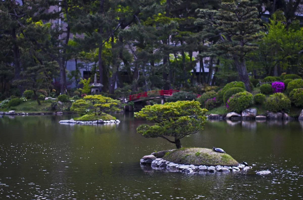 Shukkeien garden central pond reflecting teahouses and trees in the historic Hiroshima strolling garden Japan