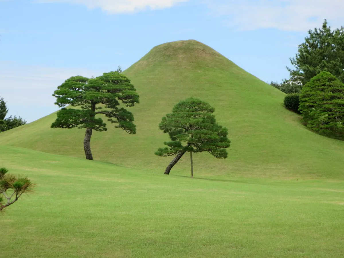 Miniature Mount Fuji grass mound reflected across the spring-fed pond at Suizenji Garden in Kumamoto, Japan