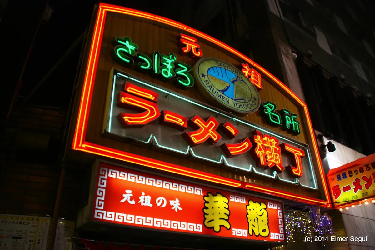 Sapporo Ramen Yokocho narrow alley with glowing lanterns and miso ramen stall signs in Susukino entertainment district Japan