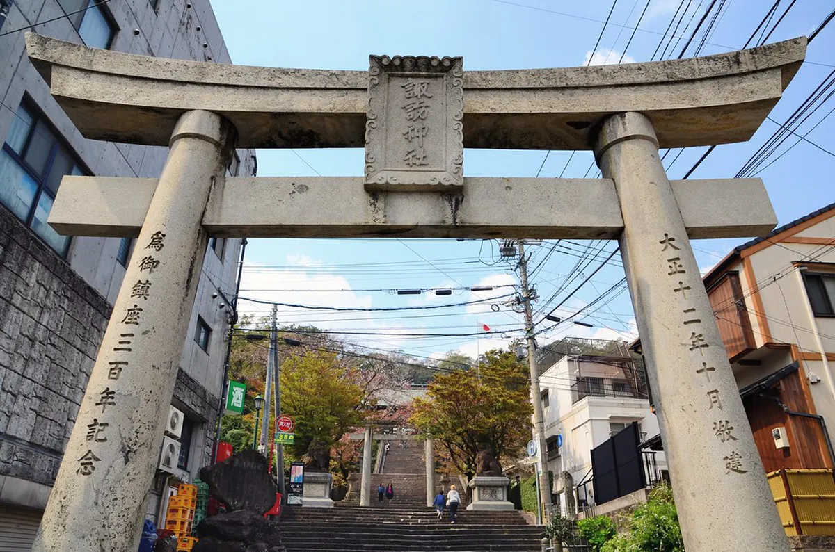 Suwa Shrine torii gate framed by stone lanterns along the staircase path in Nagasaki, Japan
