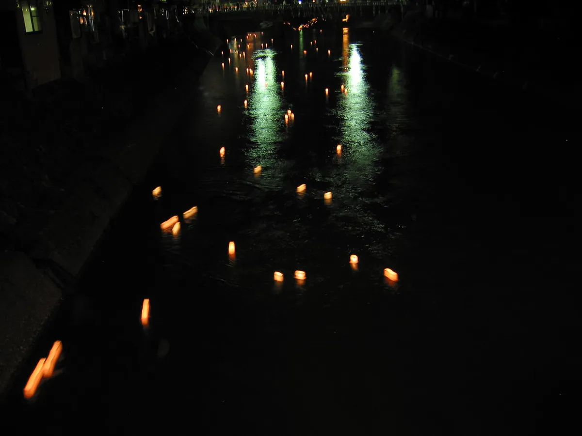 Traditional lanterns reflecting on the calm Miyagawa River at night in historic Takayama, Japan