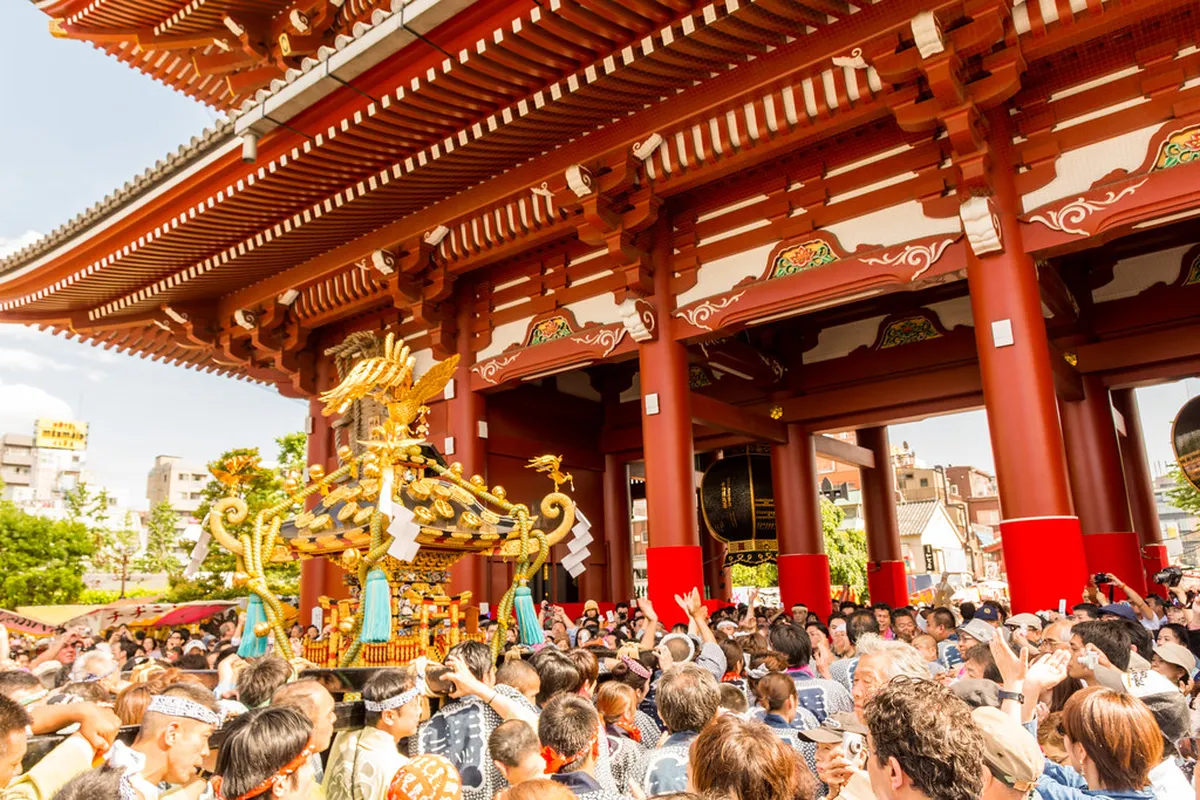 Crowds carrying ornate portable mikoshi shrines through the streets of Asakusa during the Sanja Matsuri festival in Tokyo, Japan