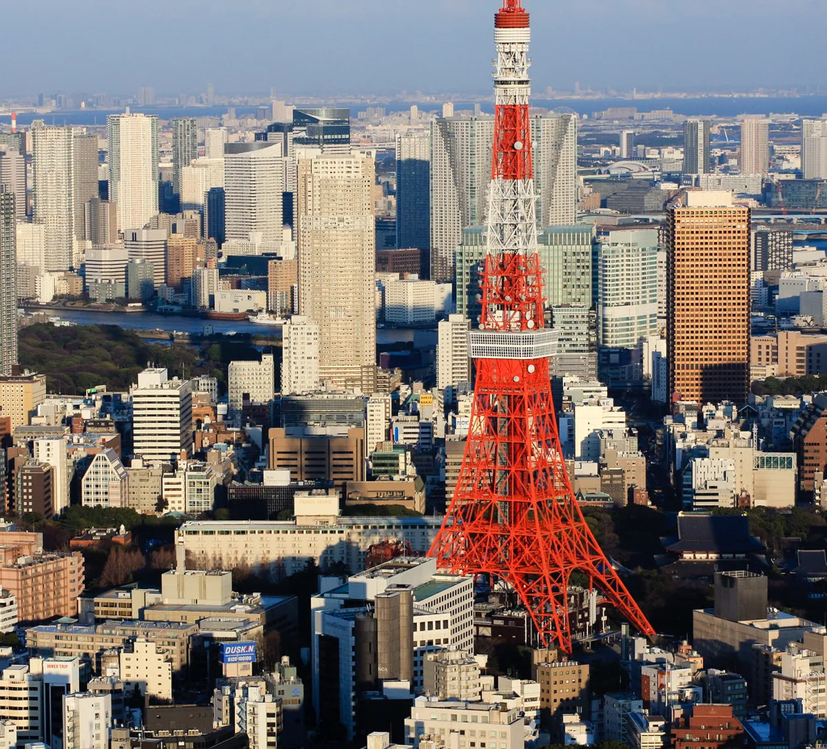 Tokyo Tower red-and-white lattice structure rising above Minato City skyline at dusk in Japan