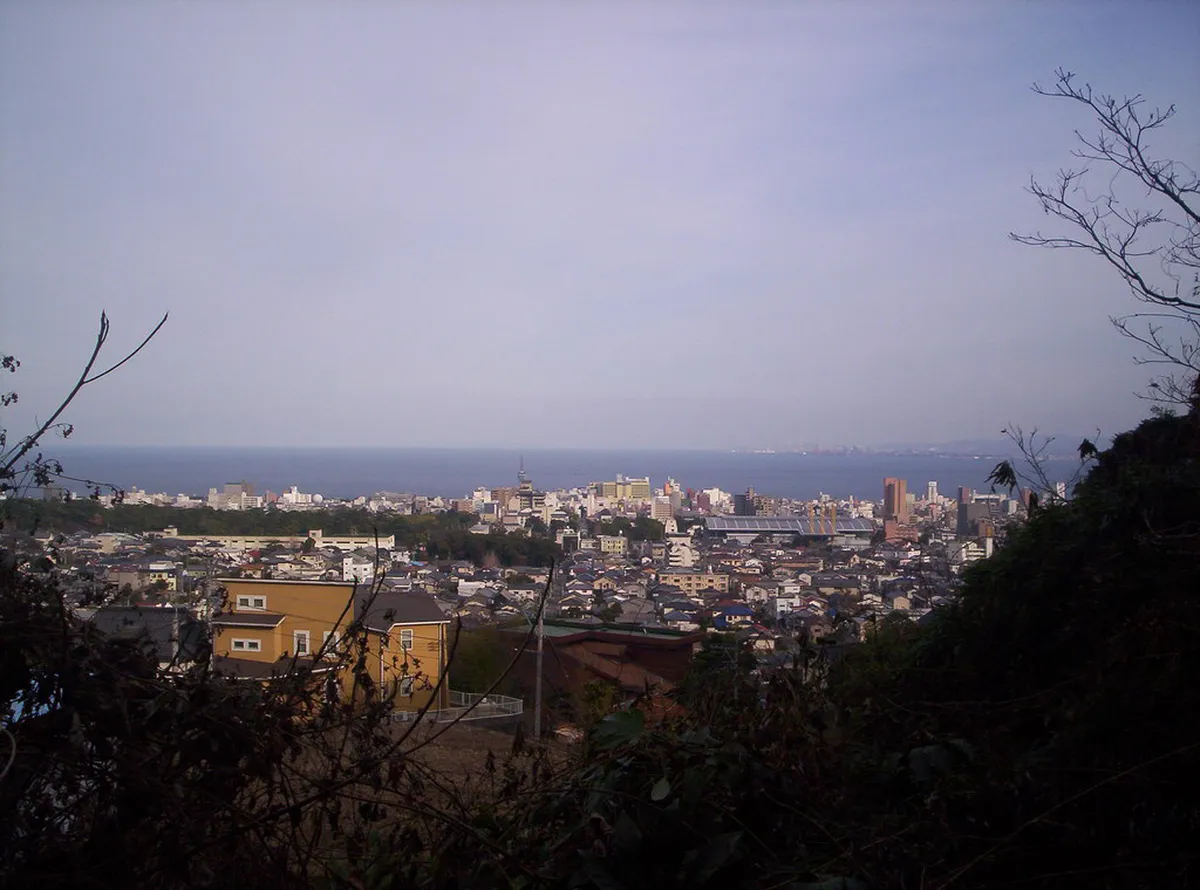 Panoramic view over Beppu onsen city with steam rising from hot springs against the coastal backdrop, Japan