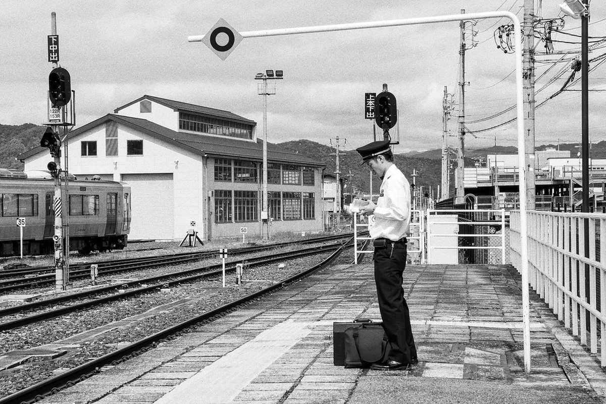 Takayama Station entrance with traditional wooden facade and mountains visible in the background, Japan
