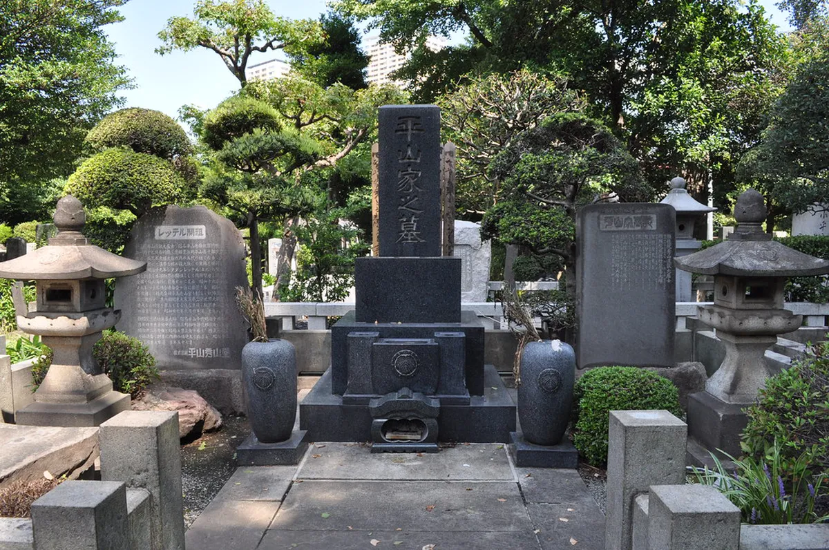 Yanaka Cemetery tree-lined path in Tokyo with gravestones and verdant foliage on a quiet afternoon