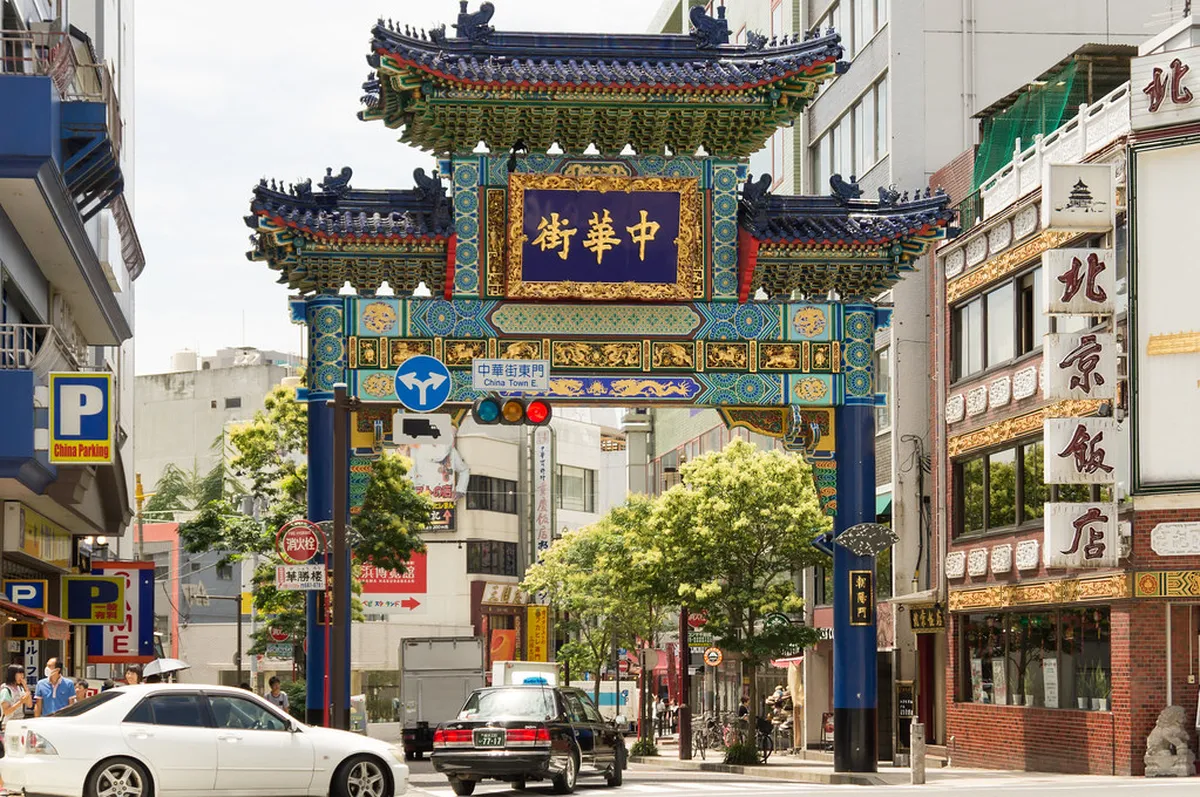 Steaming street food stalls selling dumplings and buns along a busy Yokohama Chinatown lane, Japan