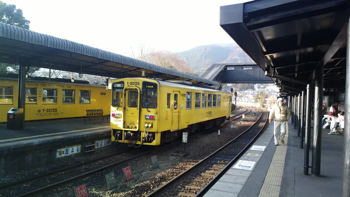 Yufuin Station with its distinctive timber architecture and Mount Yufu visible in the background in Japan