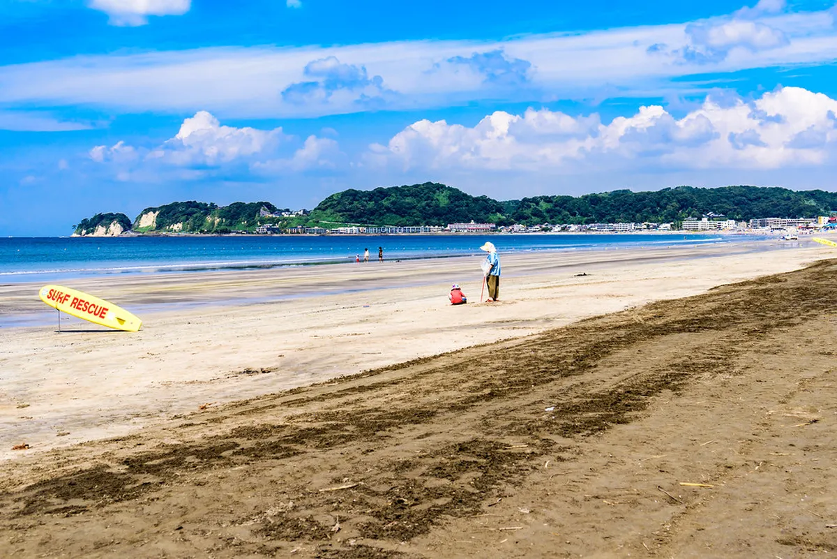 Colorful beach huts and sunbathers enjoying the summer season at Kamakura's busy Pacific-facing shoreline